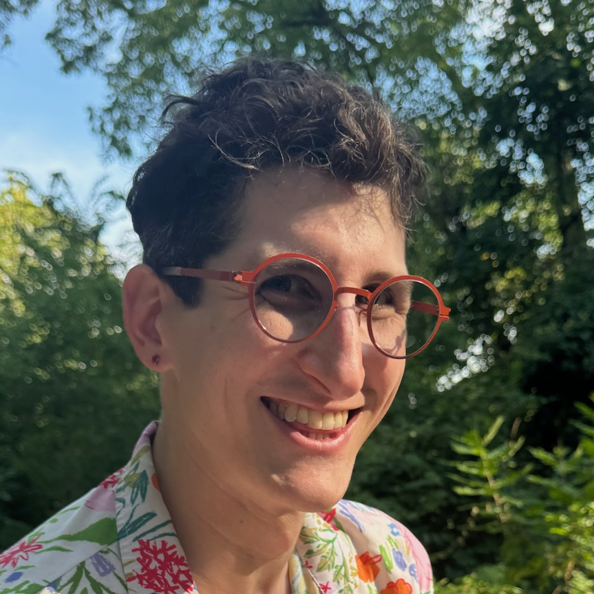 xena, and wearing glasses and a floral shirt, smiles at the camera